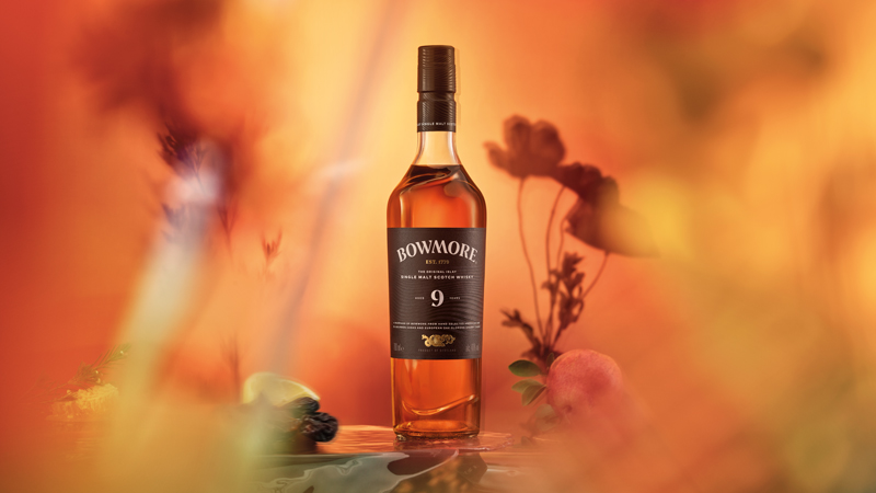 Flasche des Bowmore 9 Years Old in einem Blumenfeld in orangenem Licht
