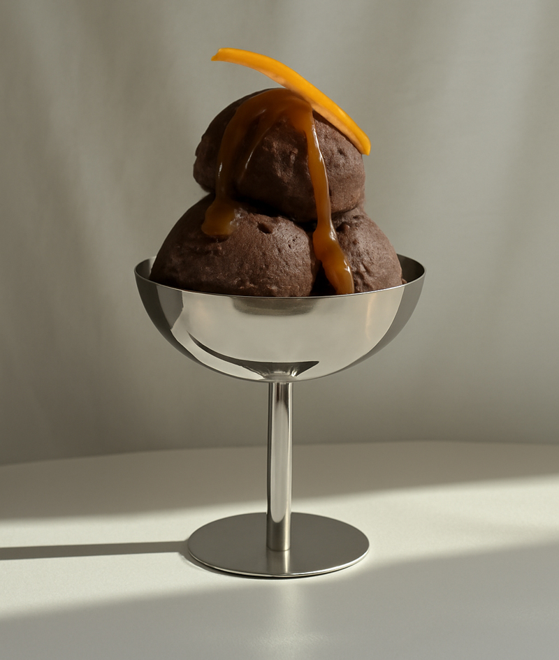 3 Kugeln Schokoladen-Eiscreme mit dunkler Schokoladensoße in einem Metalleisbecher