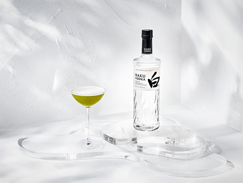 Haku Voddka Flasche mit Haku Matcha Cocktail im Glas auf einem Glastisch
