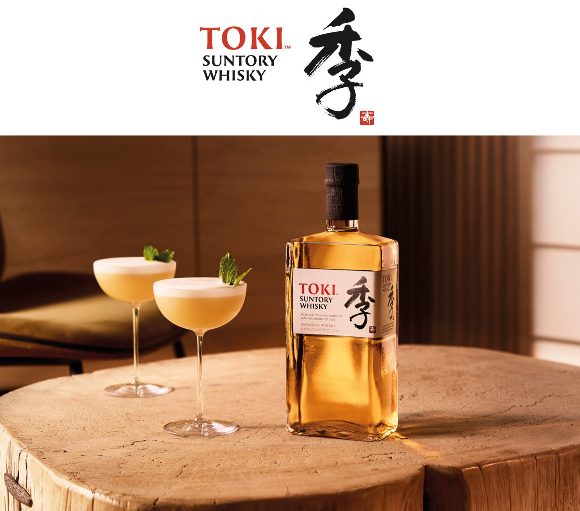 Toki Whisky Flasche und zwei Gläser mit dem Cocktail Toki Sour auf einem Holz-Tisch